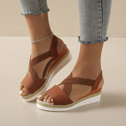 Brown wedge sandals worn with light blue jeans on a beige background
