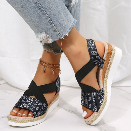 Black bandana-patterned sandals with jute sole worn by a person on a white background
