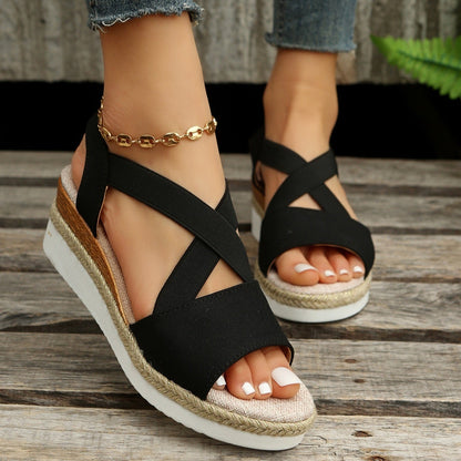 Black strappy sandals with cork sole on a wooden floor