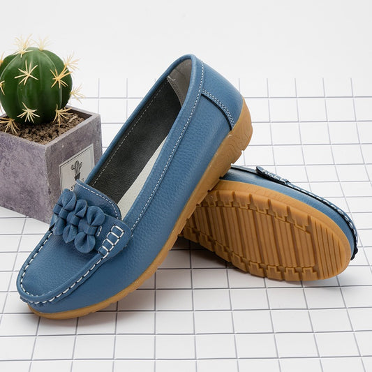 Blue loafers with brown soles on a checkered floor with a cactus plant.
